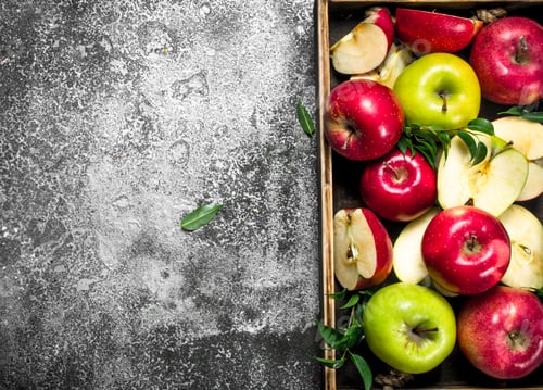 Preview: Red and green apples in a wooden tray.