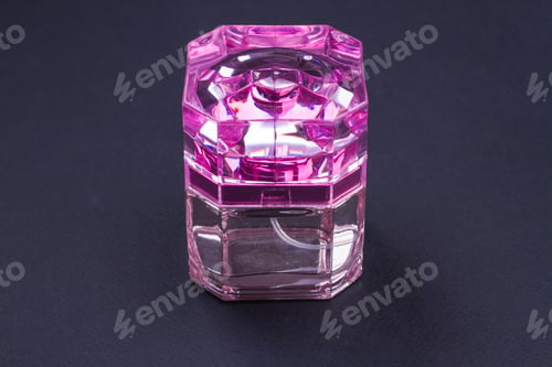 Preview: Women's perfume in bright pink bottle on dark background.