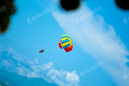 Preview: Colorful Parasailing Parachute High in Clear Blue Sky