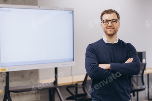 Preview: Professional businessman smiling, crossing arms while standing in sleek blank display screen