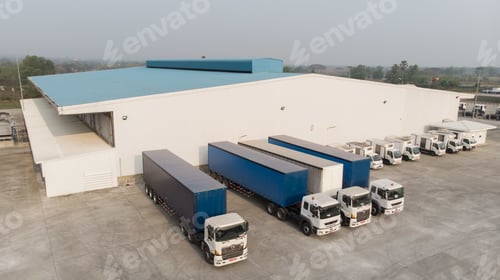 Preview: Aerial shot of factory trucks near a white building with a clear sky in the background