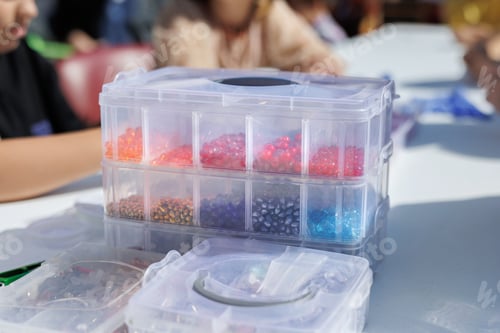 Preview: Children make jewelry with their own hands, stringing colorful beads on a string.