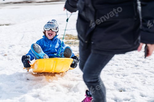 Preview: Excited son riding sledge near mother