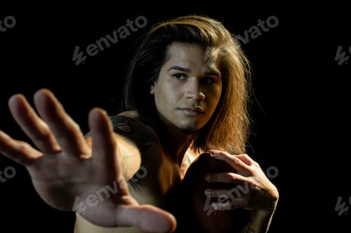 Preview: Portrait of bare chested young man with football, black background