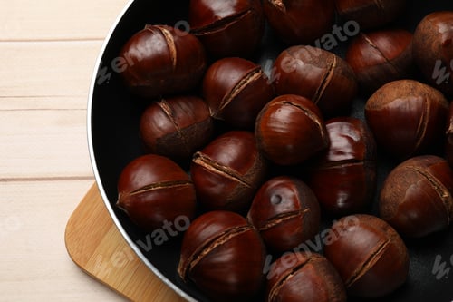 Preview: Roasted edible sweet chestnuts in frying pan on wooden table, top view