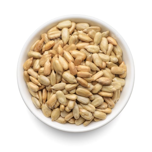 Preview: Peeled sunflower seeds in white bowl isolated on white. Top view.
