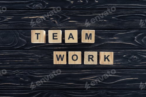 Preview: top view of word team work made of wooden blocks on dark wooden tabletop