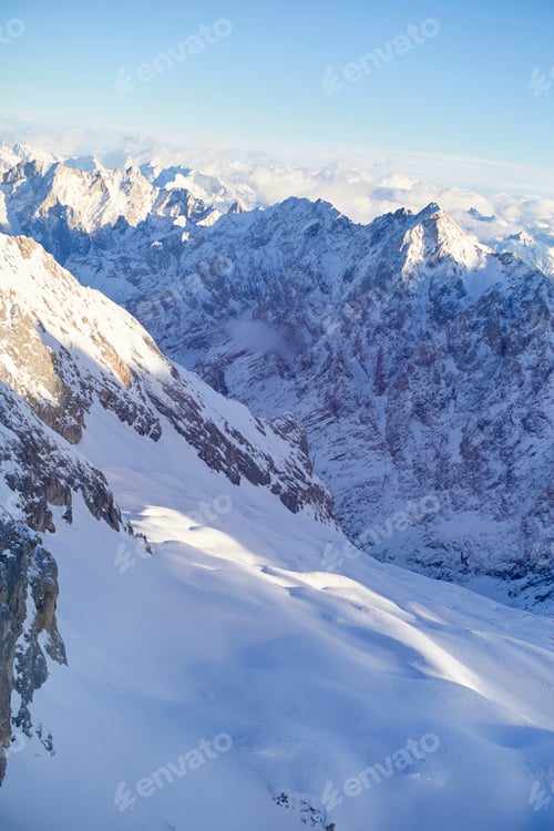 Preview: The image shows a majestic snowy mountain range with sharp peaks and a clear blue sky.