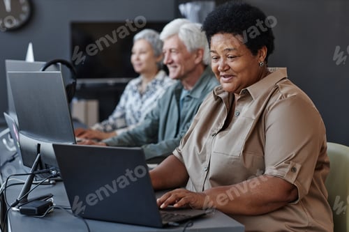 Preview: Senior black woman using computer and smiling in computer class for elderly