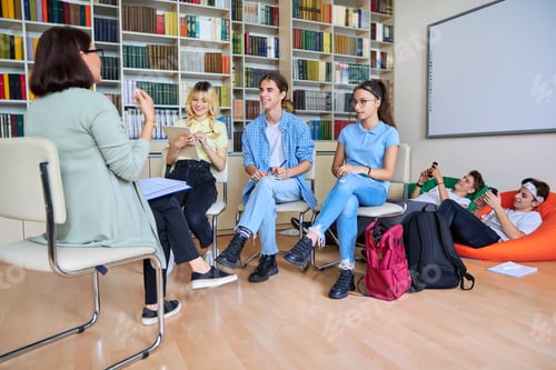 Preview: Female mentor teacher working with male teenage high school students in library