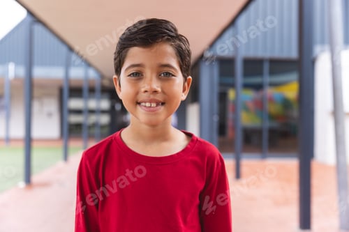 Preview: In school, biracial young boy with a bright smile standing outside
