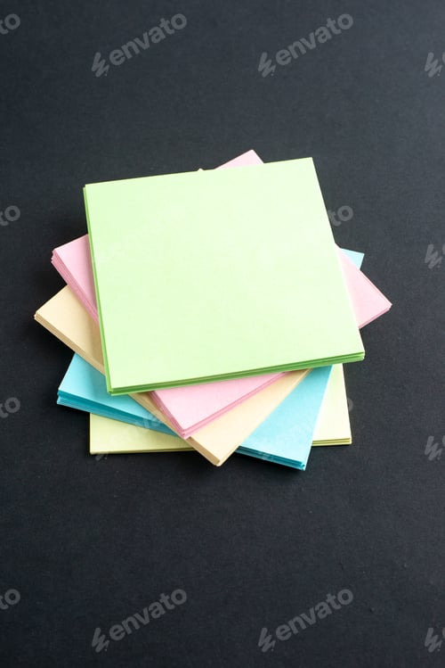Preview: Side view of stacked sticky coloured note cubes on isolated black wave background with free space
