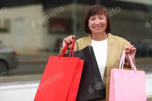 Preview: Seasonal Sales. Happy adult woman with shopping bags. Middle ages female after shopping on shopping