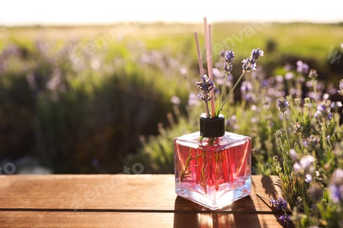 Preview: Bottle of air freshener on wooden table in lavender field. Space for text
