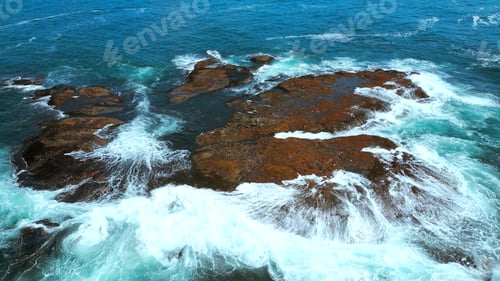 Preview: Aerial view of ocean waves crashing into rocks. Clip. Flying above turquoise water and giant
