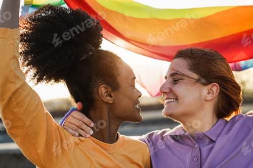 Preview: Happy women gay couple holding rainbow flag outdoor - Love and lesbian concept