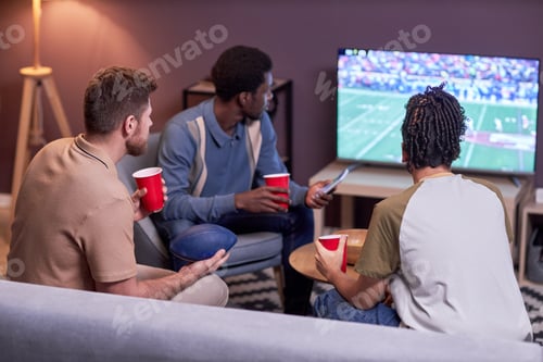 Preview: Diverse group of friends watching American football match on TV at home
