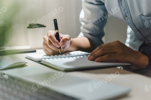 Preview: man hands with pen writing on notebook in the office.learning, education