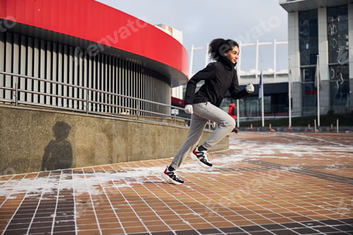 Preview: Female athlete sprinting forward on a city square