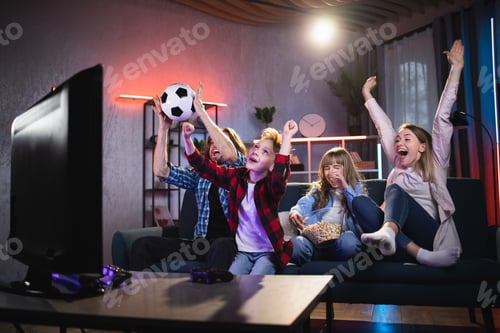 Preview: Excited family of four watching soccer on television