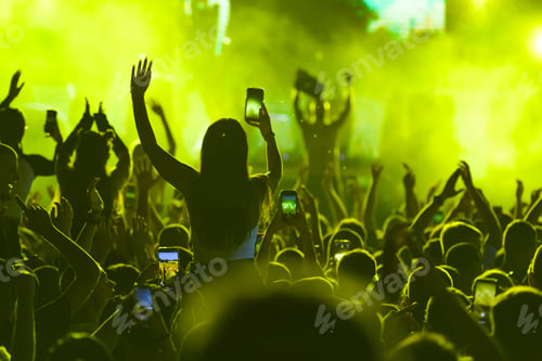 Preview: Vibrant yellow-lit concert crowd with waving hands