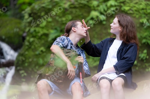Preview: Young couple hiking in the forest with backpacks and trekking poles