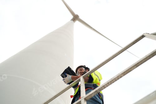 Preview: Wide perspective of wind turbine engineers walking with coworker in wind farms