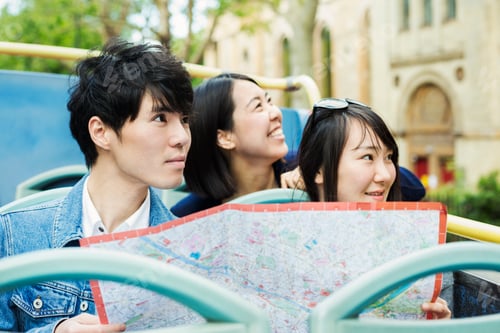 Preview: Three tourists holding a city map, sitting on the top of an open Double-Decker bus