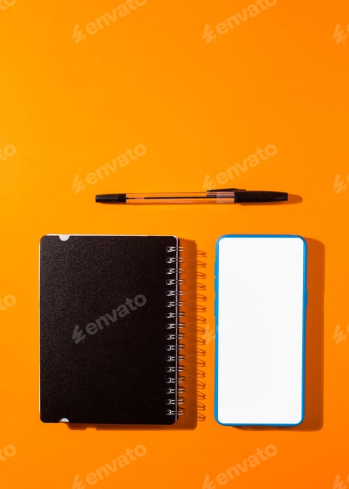 Preview: Vertical shot of a smartphone and a notepad with a pen on an orange background