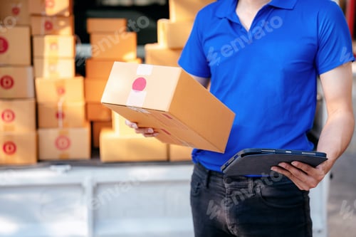 Preview: A man in a blue shirt is holding a cardboard box and a tablet