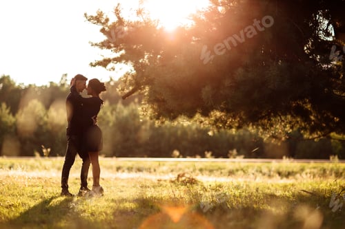 Preview: Young couple in love walking in the summer park holding hands. woman and man dressed in black