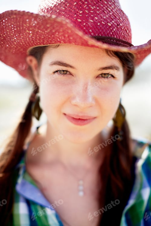 Preview: A young woman in denim jacket and boots on the hood of a tractor.
