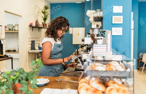 Preview: Young woman managing cafe with digital tablet