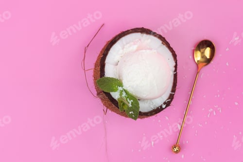 Preview: Vanilla ice cream balls in a fresh coconut half decorated with mint leaves with a spoon on a pink