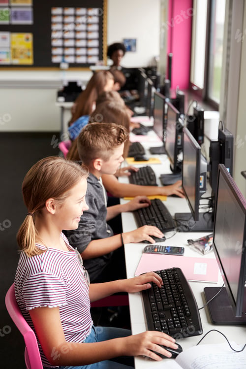 Preview: Line Of High School Students Working at Screens In Computer Class With Female Teacher In Background