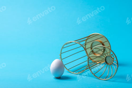 Preview: Upside down open cage with an egg outside on a blue background