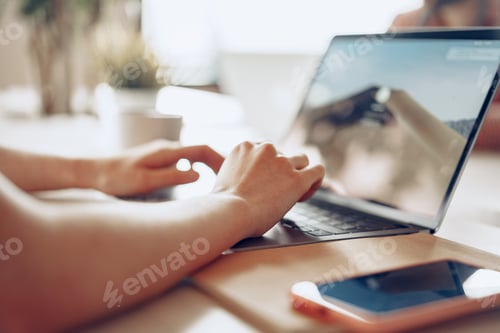 Preview: Close up of a woman typing on laptop while sitting at the table in office