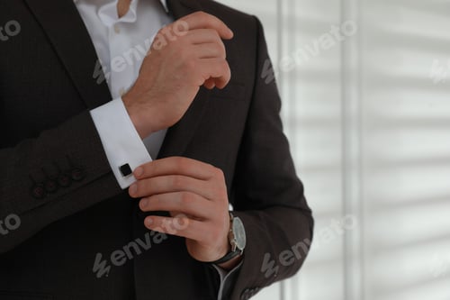 Preview: Man wearing stylish suit and cufflinks near white wall, closeup. Space for text