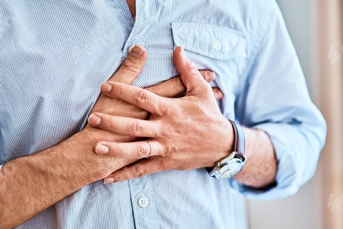 Preview: Shot of a unrecognizable man holding his chest in discomfort due to pain at home during the day