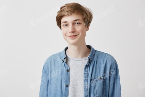 Preview: Friendly young man smiles at good joke, has fair hair and blue eyes, dressed casually, looks with