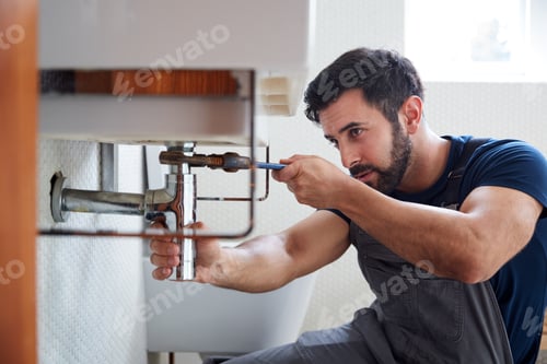 Preview: Male Plumber Using Wrench To Fix Leaking Sink In Home Bathroom