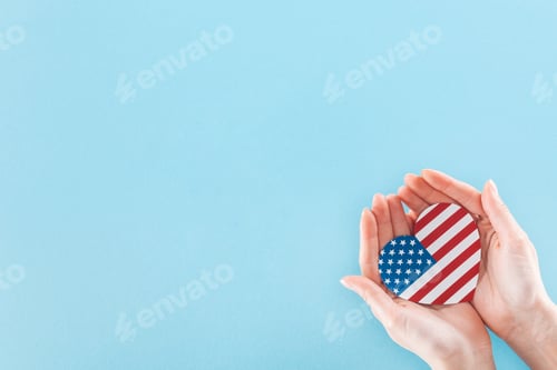 Preview: cropped view of woman holding heart made of national american flag on blue background with copy
