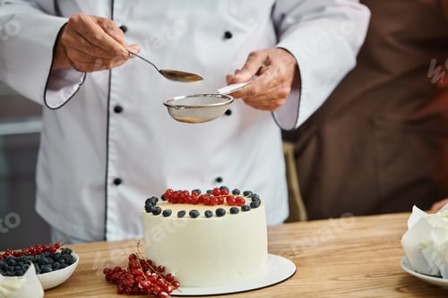 Preview: cropped view of mature male chef decorating his delicious cake professionally, cooking courses