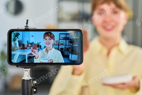 Preview: Focus on smartphone screen with happy young woman holding handmade soap