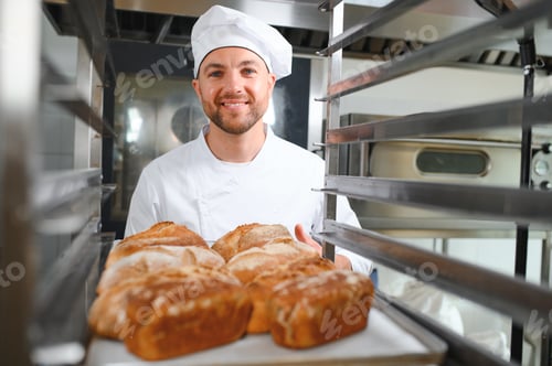 Preview: Male baker holding a tray of baked breads in bakery shop