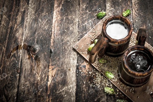 Preview: Beer in a wooden mug with green hops.