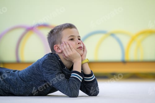 Vista previa: Young child boy laying down and relaxiong while resting on the floor inside sports room