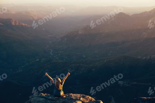 Preview: Person on mountain peak at sunset with arms raised