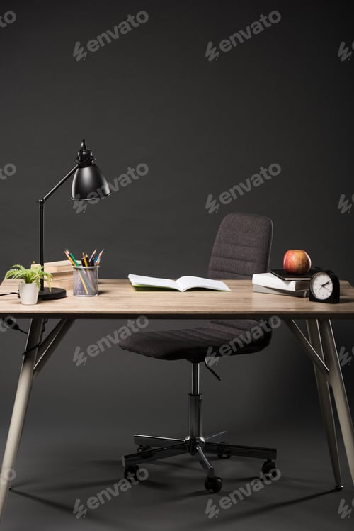 Preview: front view of table with lamp, plant, books, colour pencils, eyeglasses, empty textbook, apple and