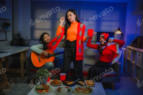Preview: Friends celebrating Christmas party at home, women dancing and playing guitar in festive mood